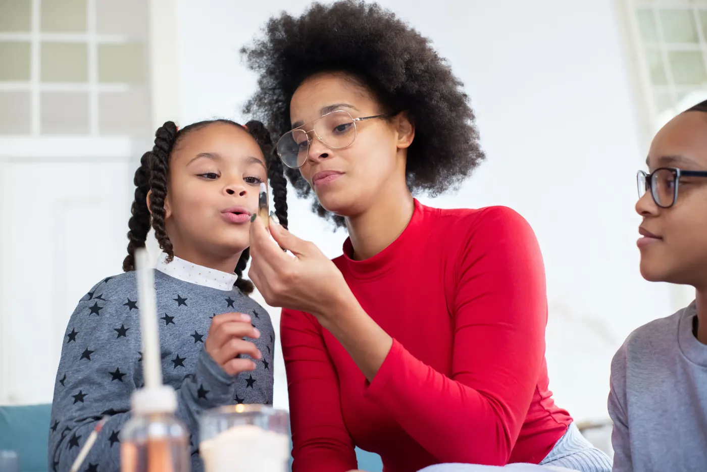 A mom and two kids leaning in together over a hands-on science activity at home