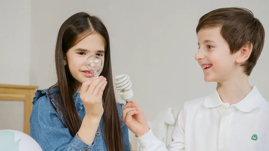 Two kids holding up a paper light bulb idea sign